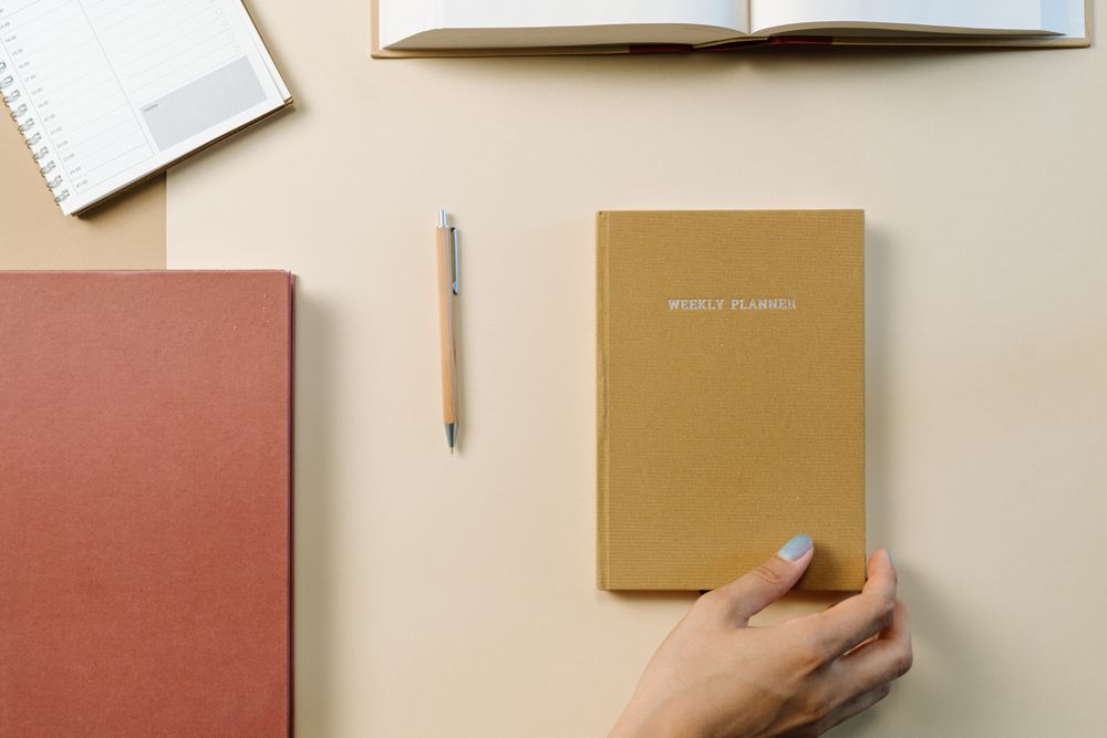 A weekly planner and notebook on a desk
